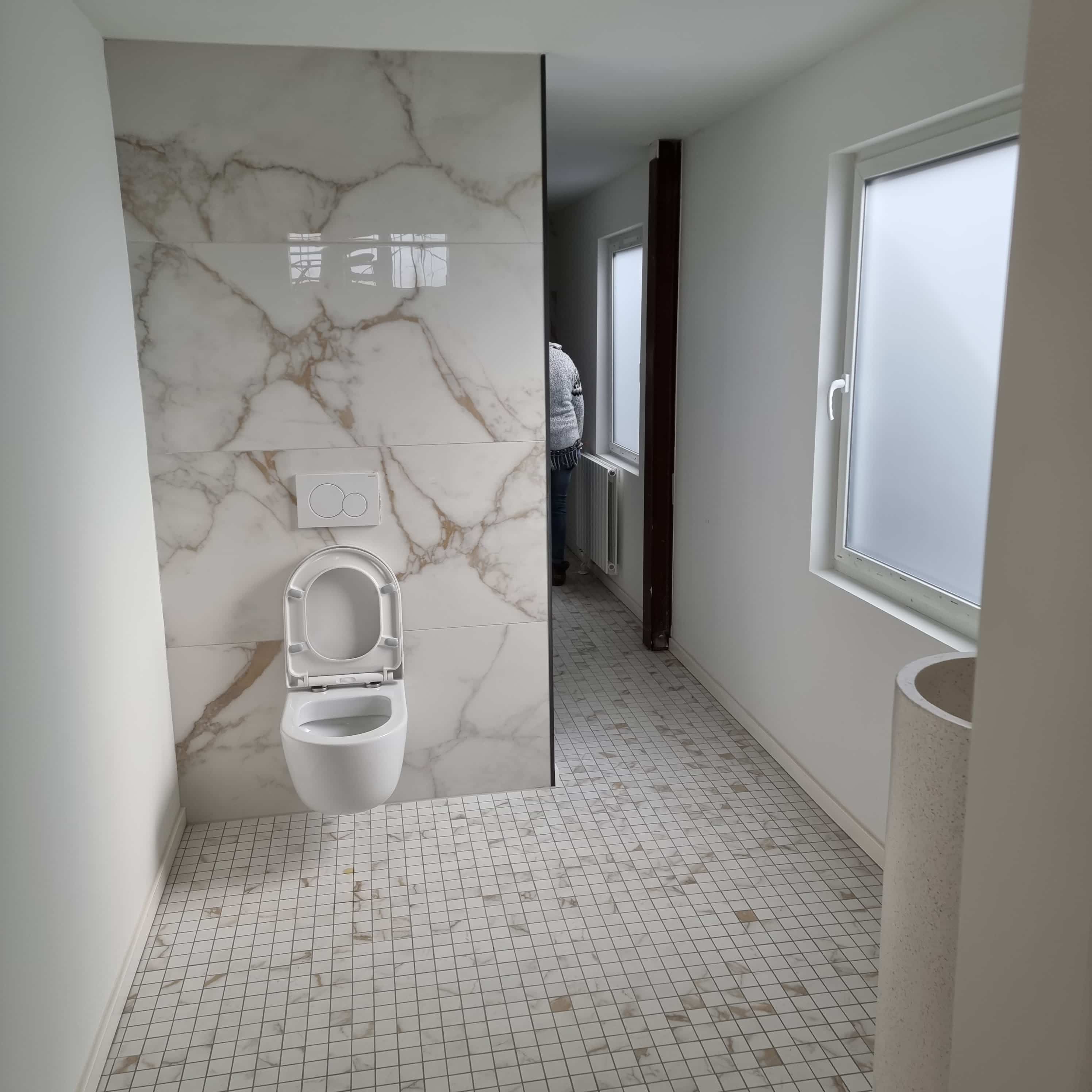 A toilet with white marble tiles and white floor