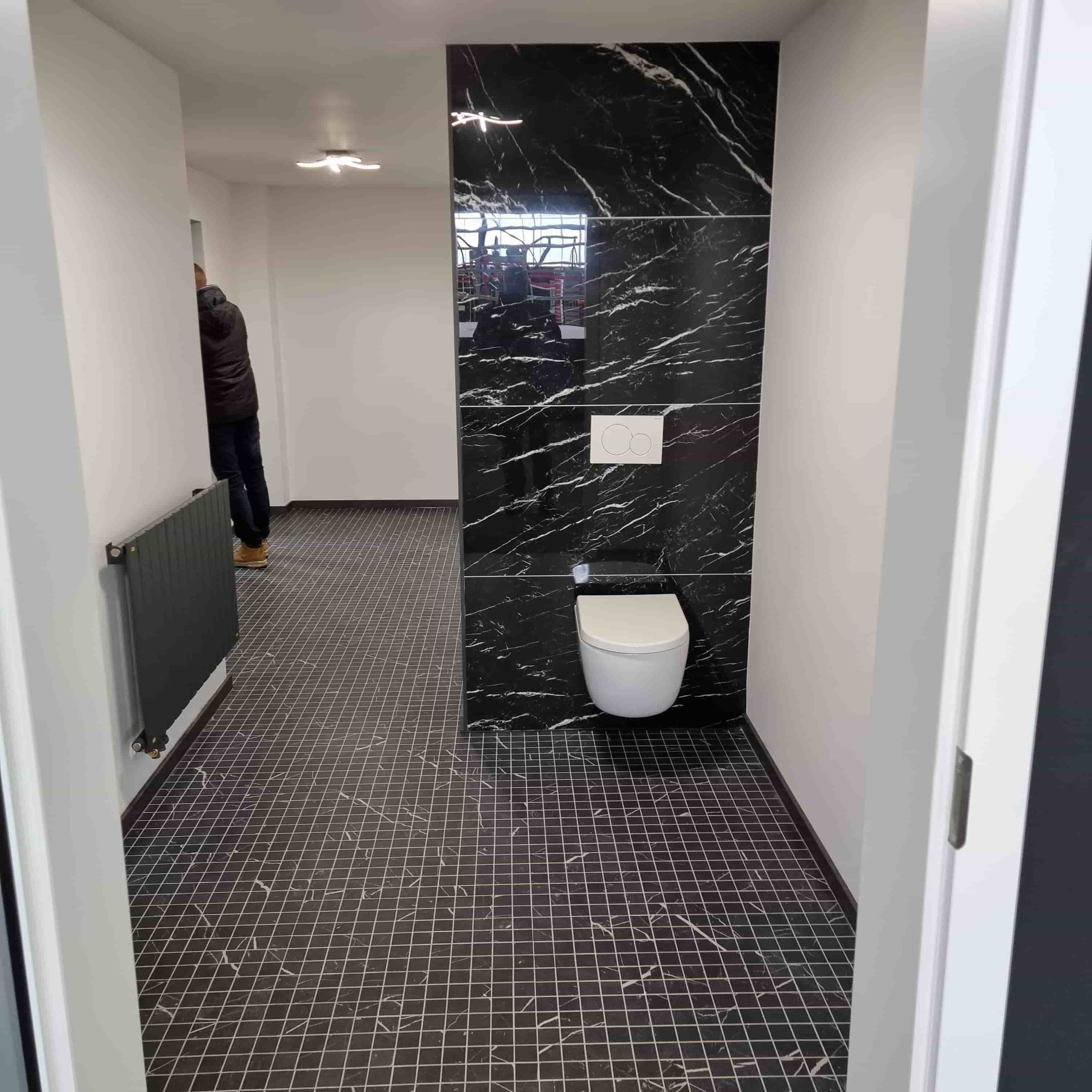 A toilet with black marble tiles and black floor