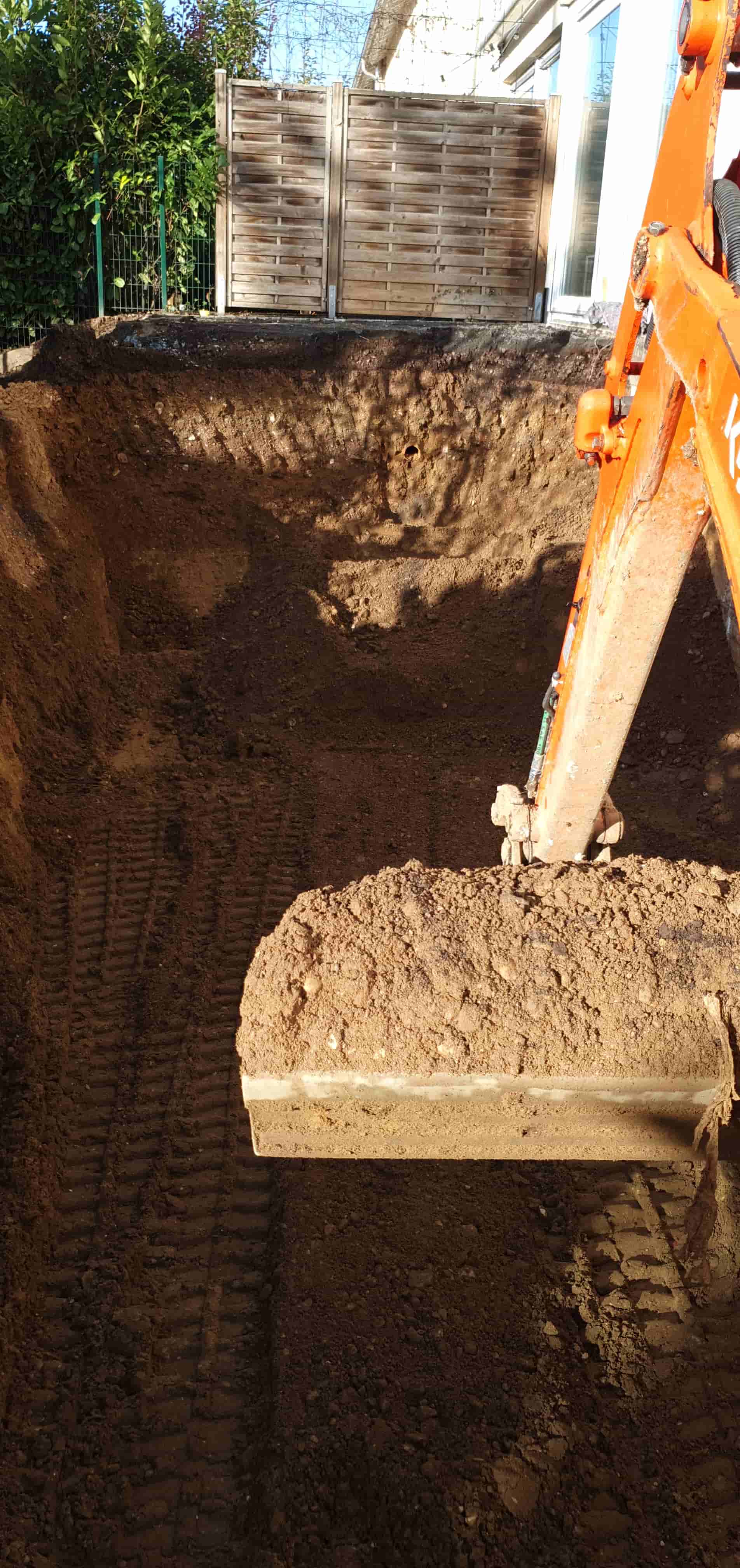 Eine Baggerschaufel hebt Erde aus einem Loch.